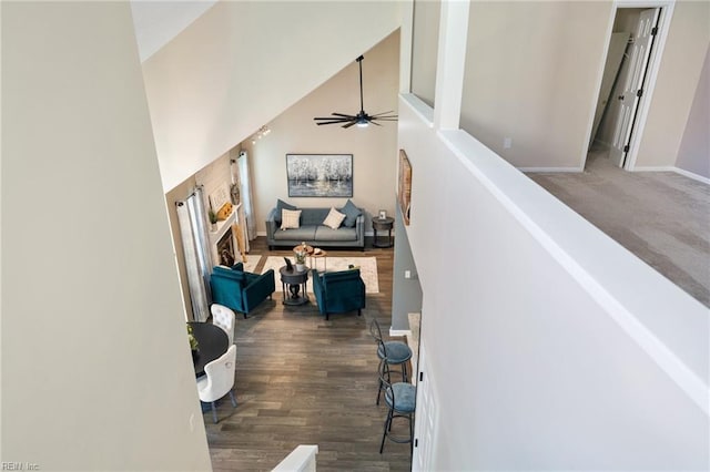 stairs with hardwood / wood-style floors, a towering ceiling, and ceiling fan