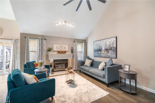 living room featuring hardwood / wood-style flooring, a large fireplace, ceiling fan, and high vaulted ceiling