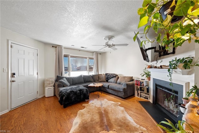 living room with hardwood / wood-style floors, a textured ceiling, and ceiling fan