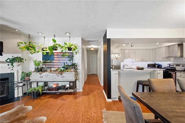 kitchen with wall chimney exhaust hood, backsplash, stainless steel appliances, light stone countertops, and white cabinets