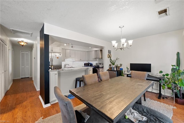 dining space with sink, a chandelier, and light hardwood / wood-style flooring