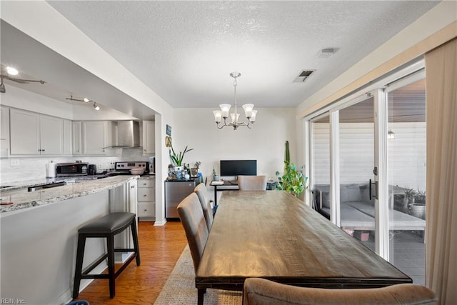 dining space featuring an inviting chandelier, a textured ceiling, and light wood-type flooring