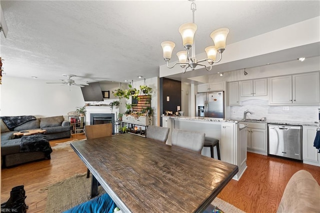 dining room with hardwood / wood-style floors, ceiling fan with notable chandelier, and sink