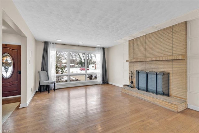 unfurnished living room with a textured ceiling, a fireplace, and light hardwood / wood-style floors