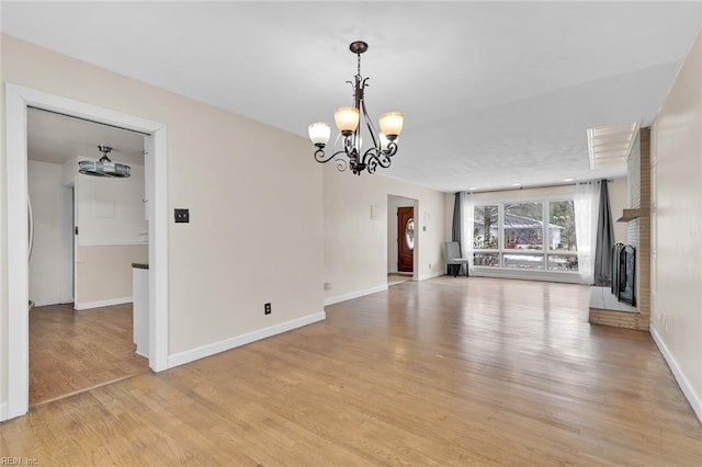 unfurnished living room with a fireplace, a chandelier, and light wood-type flooring