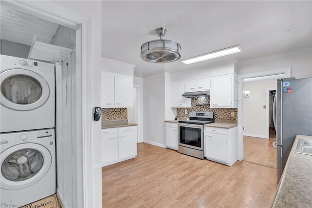 kitchen with stacked washing maching and dryer, tasteful backsplash, white cabinets, light hardwood / wood-style floors, and stainless steel appliances