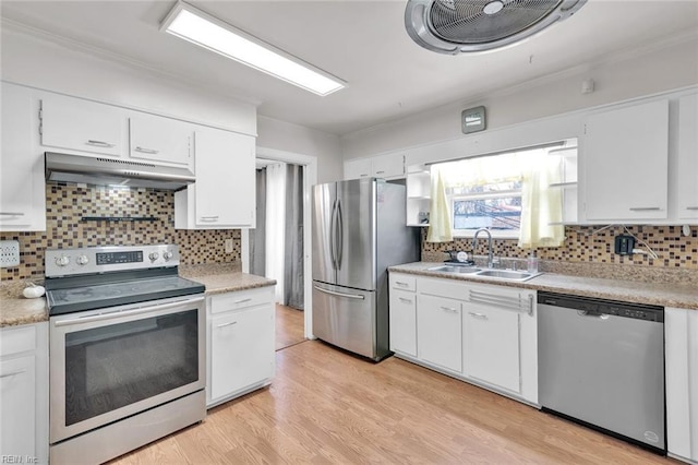 kitchen featuring appliances with stainless steel finishes, sink, white cabinets, backsplash, and light hardwood / wood-style flooring