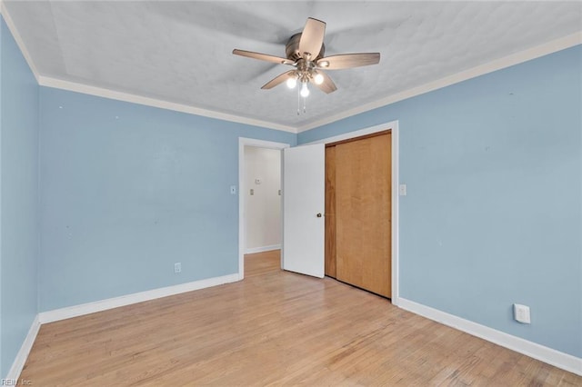 unfurnished bedroom with crown molding, ceiling fan, a closet, and light wood-type flooring