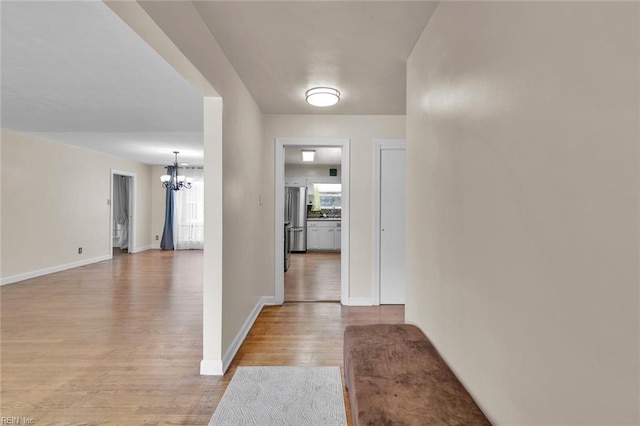 hallway with a healthy amount of sunlight, light hardwood / wood-style flooring, and a notable chandelier