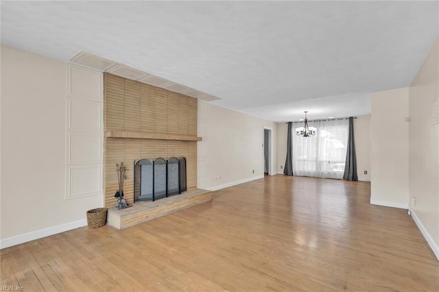 unfurnished living room featuring a fireplace, a chandelier, and light hardwood / wood-style flooring