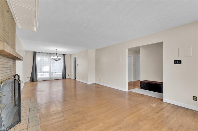 unfurnished living room featuring light hardwood / wood-style flooring, a notable chandelier, and a fireplace