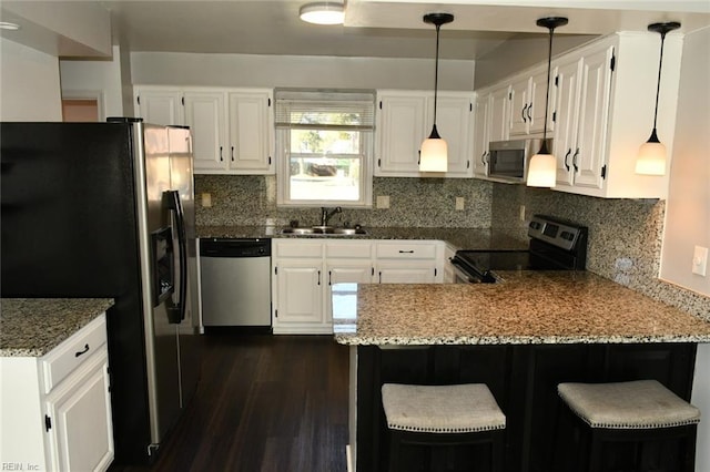 kitchen with white cabinetry, sink, a kitchen breakfast bar, kitchen peninsula, and stainless steel appliances