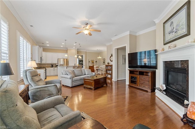 living room with hardwood / wood-style floors, crown molding, a premium fireplace, and ceiling fan