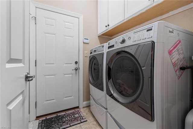 laundry area featuring washer and dryer, light tile patterned floors, and cabinets