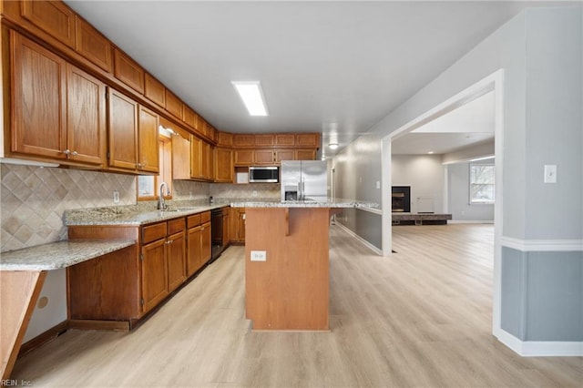 kitchen with stainless steel appliances, light stone countertops, a center island, and sink