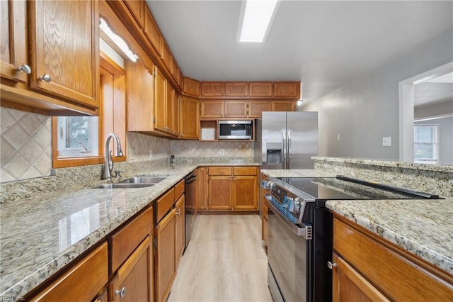 kitchen featuring light stone counters, stainless steel appliances, sink, and decorative backsplash