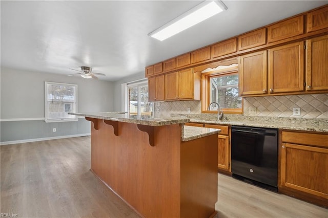 kitchen featuring sink, light hardwood / wood-style flooring, a breakfast bar, dishwasher, and tasteful backsplash