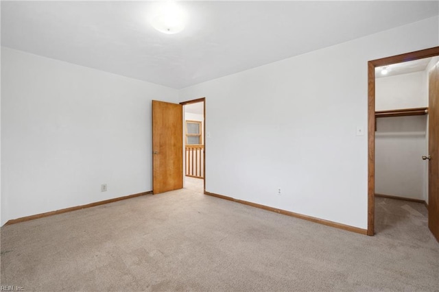 unfurnished bedroom featuring light colored carpet, a spacious closet, and a closet