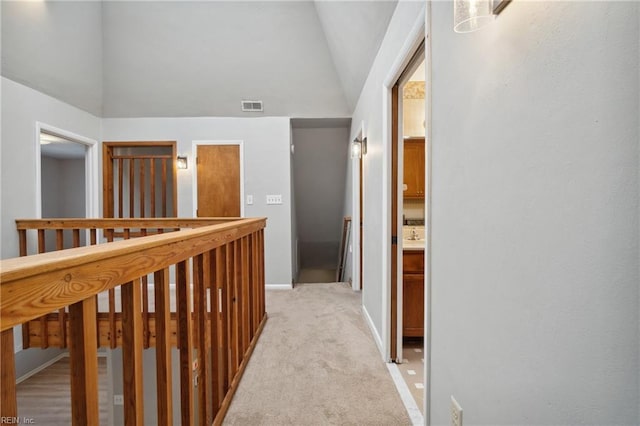 corridor featuring vaulted ceiling and light carpet