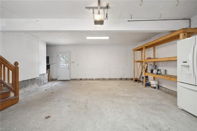 garage with a garage door opener and white refrigerator with ice dispenser