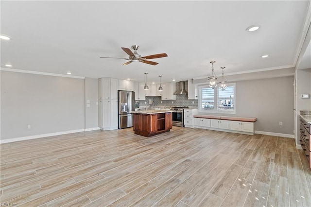 kitchen featuring sink, stainless steel appliances, a center island, decorative light fixtures, and wall chimney exhaust hood