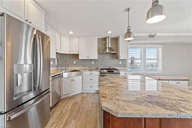 kitchen featuring a kitchen island, appliances with stainless steel finishes, decorative light fixtures, white cabinets, and wall chimney exhaust hood