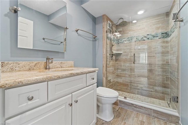 bathroom with walk in shower, vanity, and toilet