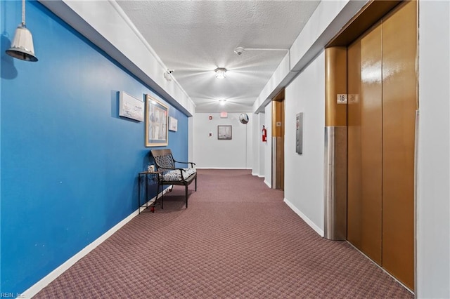 corridor featuring elevator, a textured ceiling, and dark colored carpet