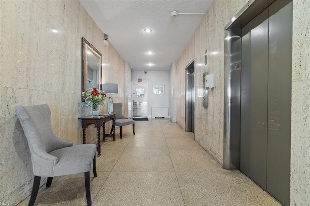 hall with elevator and a textured ceiling