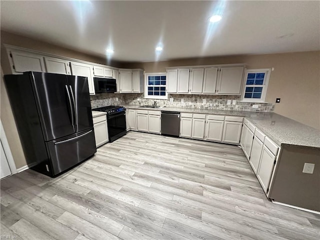 kitchen with white cabinetry, sink, backsplash, black appliances, and light hardwood / wood-style flooring