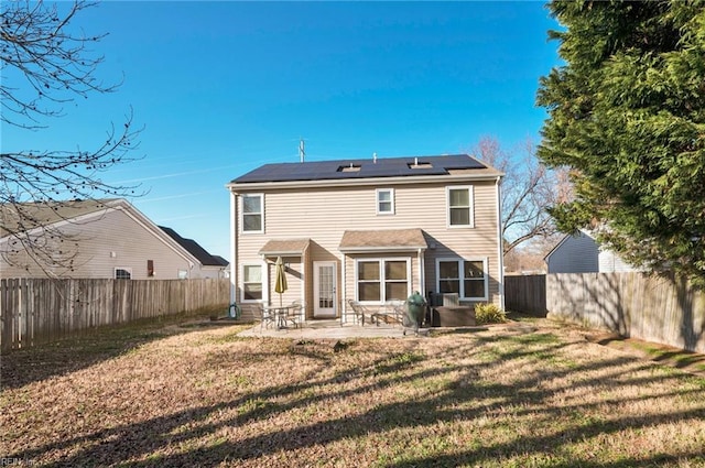 back of house with a yard, a patio, and solar panels