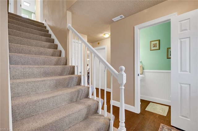 stairway with hardwood / wood-style flooring and a textured ceiling