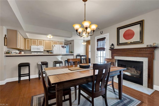 dining area featuring a fireplace, dark hardwood / wood-style floors, and a notable chandelier