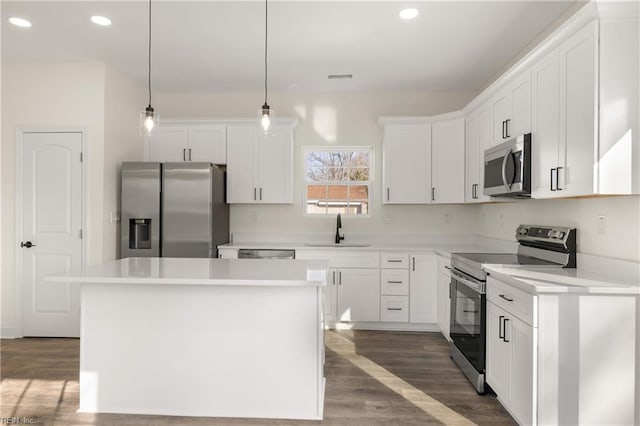 kitchen featuring white cabinetry, stainless steel appliances, hanging light fixtures, and a kitchen island