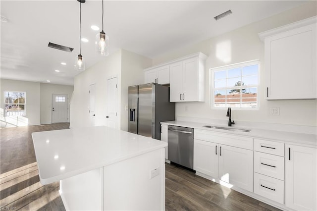 kitchen with sink, white cabinetry, dark hardwood / wood-style flooring, a kitchen island, and stainless steel appliances