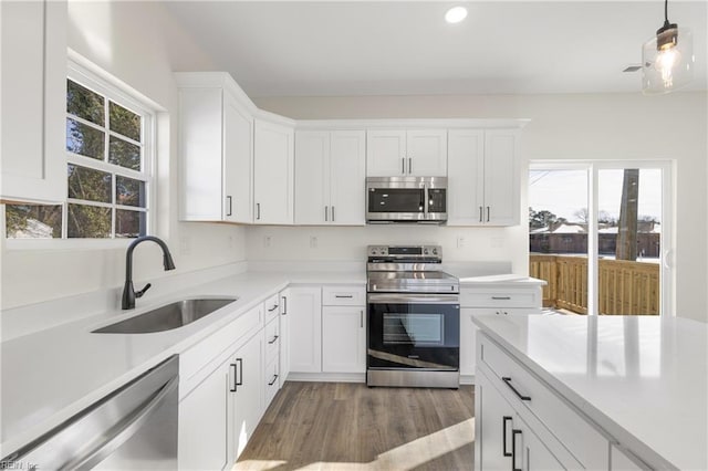 kitchen with appliances with stainless steel finishes, sink, white cabinets, and light hardwood / wood-style flooring