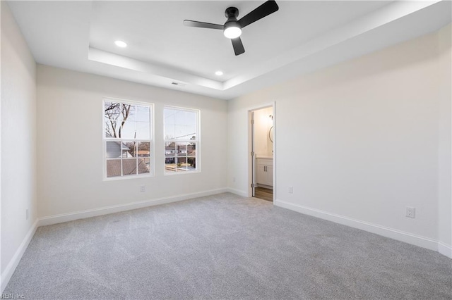 carpeted spare room featuring ceiling fan and a tray ceiling