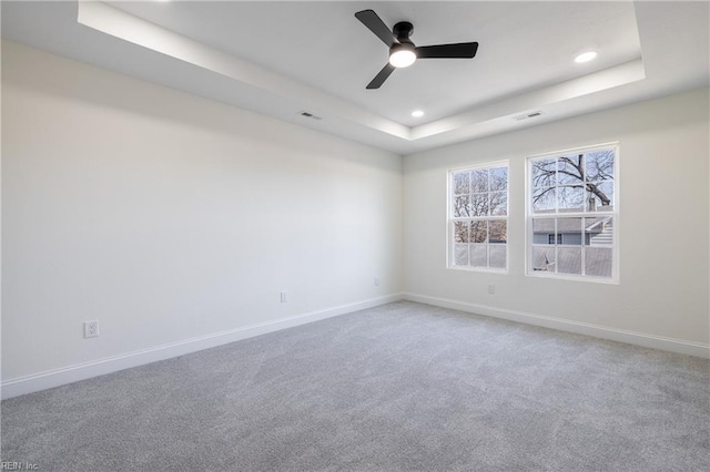 carpeted empty room featuring a tray ceiling and ceiling fan