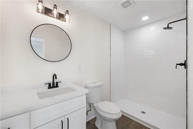 bathroom featuring tiled shower, vanity, toilet, and hardwood / wood-style floors