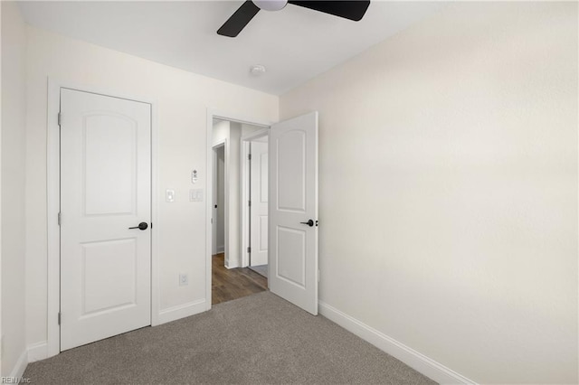 unfurnished bedroom with dark carpet, ceiling fan, and a closet