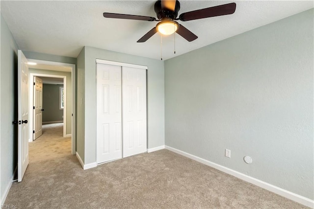 unfurnished bedroom featuring light colored carpet, a closet, and ceiling fan