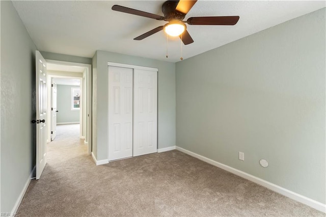 unfurnished bedroom with ceiling fan, light carpet, and a closet