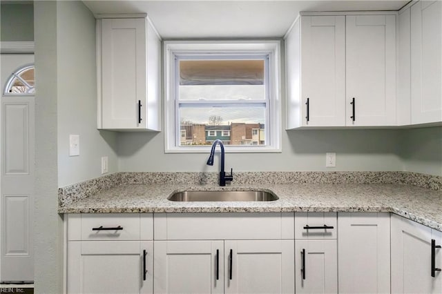 kitchen featuring light stone countertops, sink, and white cabinets