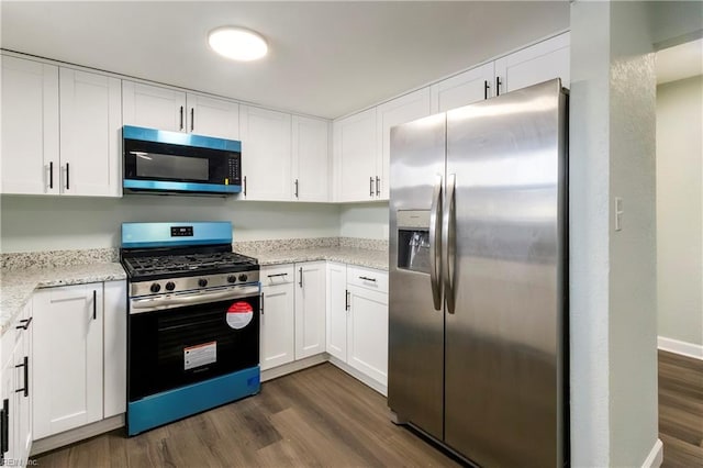 kitchen with light stone counters, appliances with stainless steel finishes, dark hardwood / wood-style floors, and white cabinets