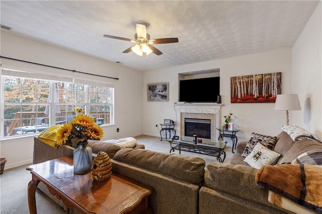 carpeted living room with ceiling fan, a premium fireplace, and a textured ceiling