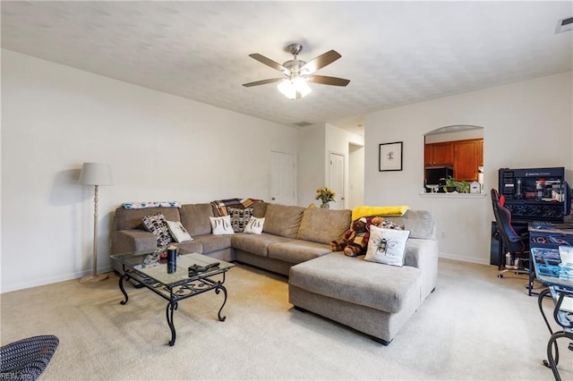 living room featuring ceiling fan, light carpet, and a textured ceiling