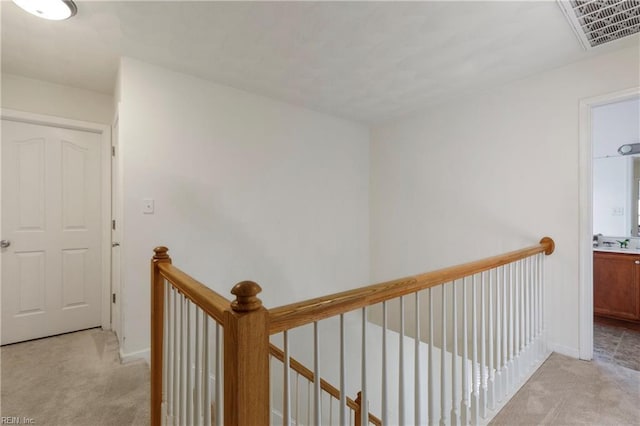 hallway with sink and light colored carpet