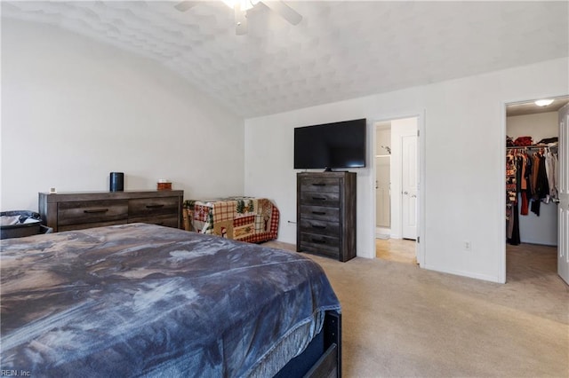 carpeted bedroom featuring lofted ceiling, a spacious closet, a textured ceiling, a closet, and ceiling fan