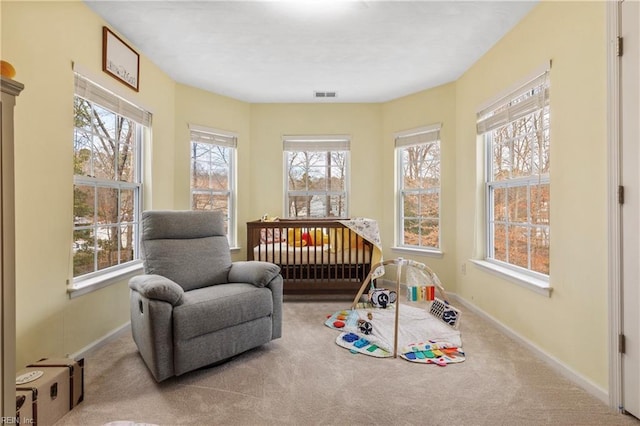 bedroom featuring light colored carpet and a nursery area