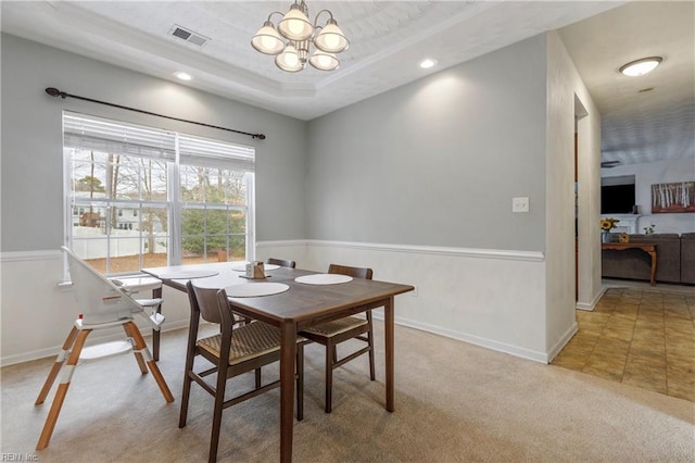 dining room with light carpet, a notable chandelier, a tray ceiling, and ornamental molding